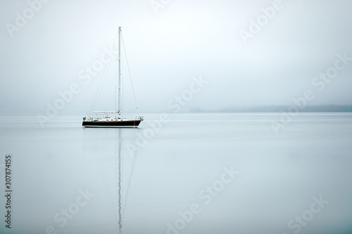 A black & white sail boat ancored in still waters photo