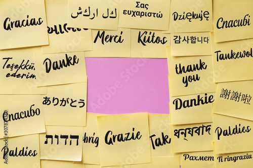 The word "thank you" on paper cards written in different languages of the world and in the center there is a place for text