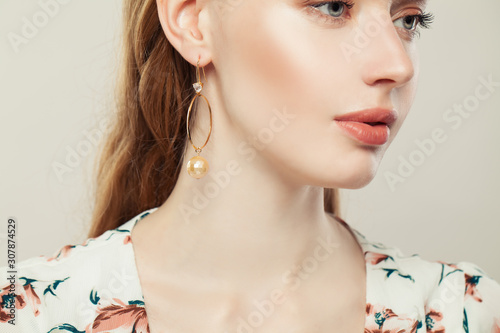 Beautiful young woman with golden earrings with pearls on white background Fototapet