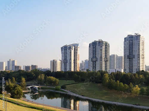 View of high buildings through a green park with a lake. City skyline
