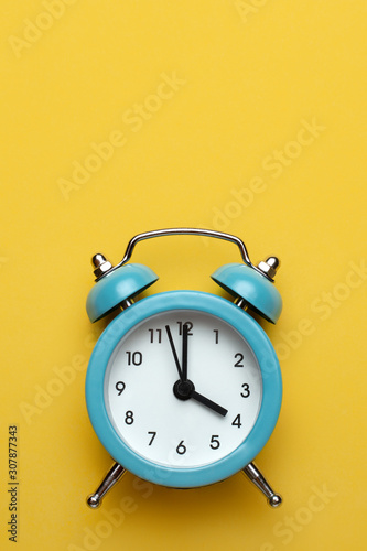 Blue round alarm clock on the cyan background.