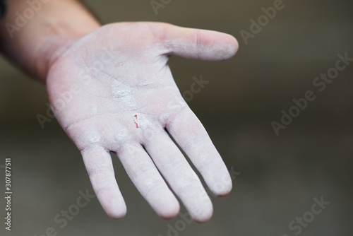 Single hand of gymnast white chalk powder against dark background. Athlete getting ready for training.