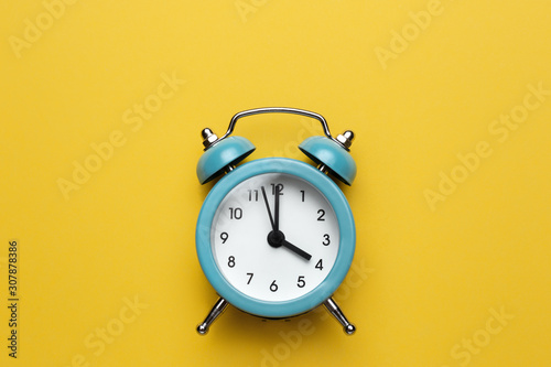 Blue round alarm clock on the cyan background.