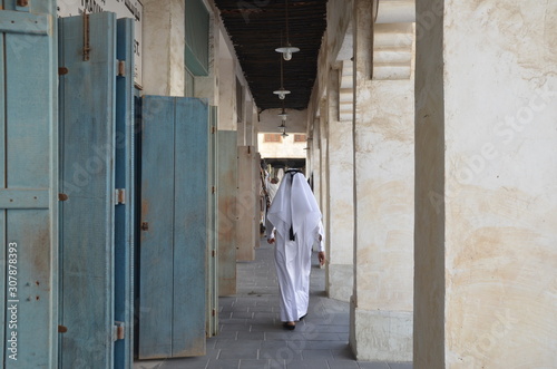 An Arabian man walking toward the end of the street at old soak of Doha. photo