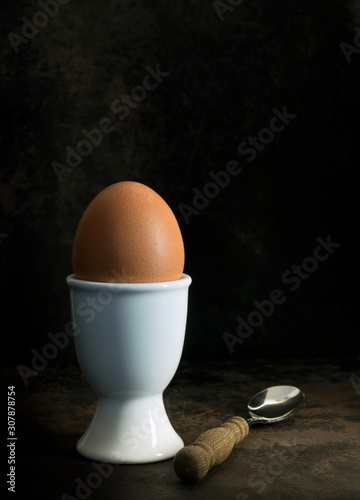 A low light image of a boiled egg in a cup on a dark background with copy space for your text photo