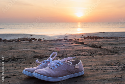 close-up canvas shoes on a beach at sunrise, travel