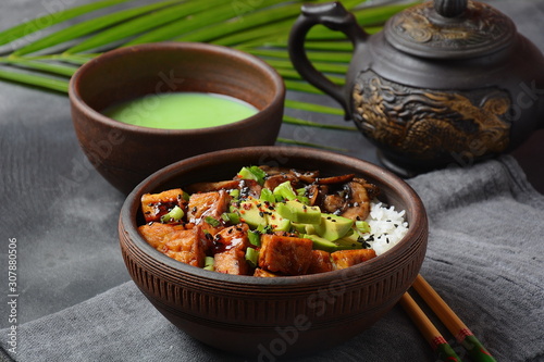 Sweet, spicy , crispy and fried Tofu in a bowl with terriayaki sauce, avocado,fried mushrooms, sesame seeds and rice. Served with green Matcha Tea. Healthy vegan food, gluten-free