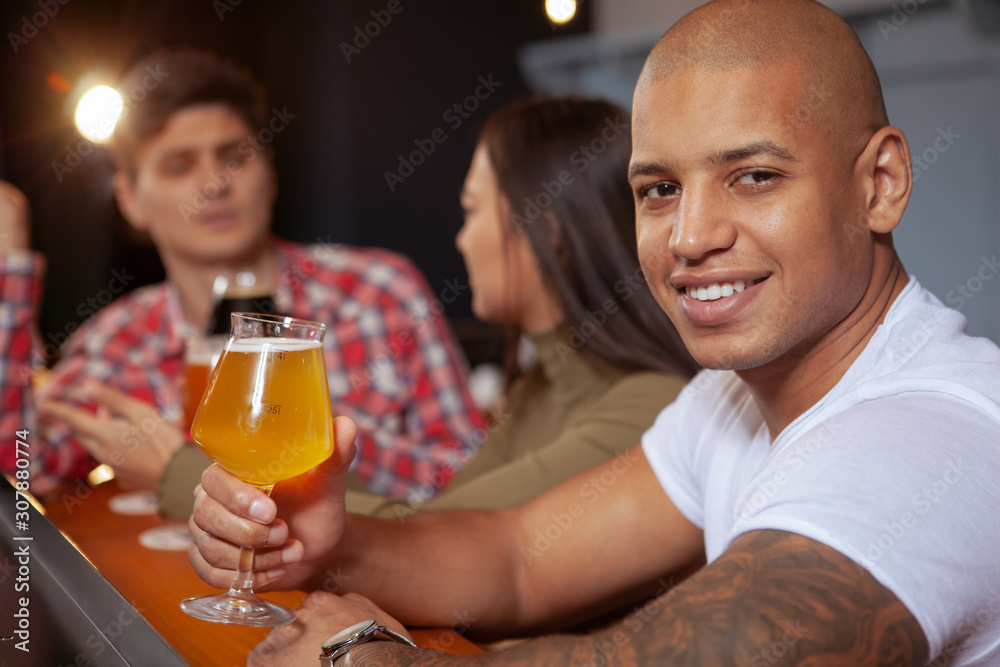 Cropped shot of an attractive young African man holding up his beer glass, drinking at the pub