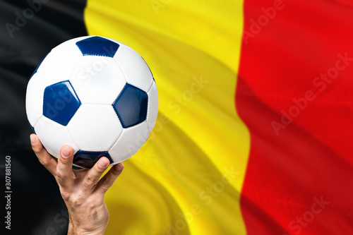 Belgium soccer concept. National team player hand holding soccer ball with country flag background. Copy space for text.