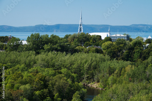 Église Saint-Patrice et rivière du Loup vus du parc des chutes avec fleuve Saint-Laurent derrière et montagnes de Charlevoix. St Patrice church viewed from waterfall park with St Lawrence river behind photo