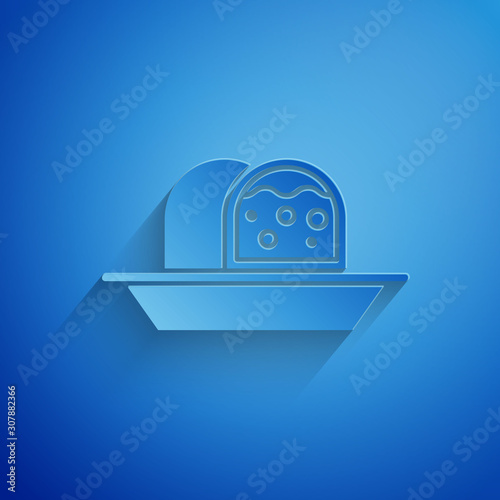 Paper cut Marzipan sponge cake icon isolated on blue background. Merry Christmas and Happy New Year. Paper art style. Vector Illustration