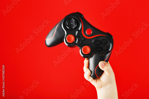 A child's hand triumphantly holds the gamepad on a red background.