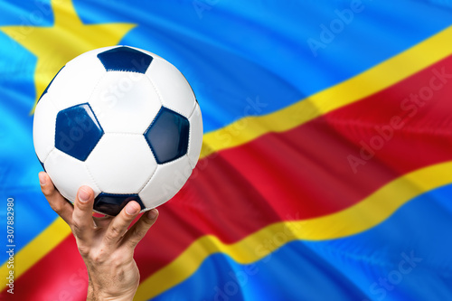Congo soccer concept. National team player hand holding soccer ball with country flag background. Copy space for text.