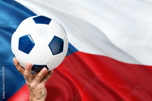 Czech Republic soccer concept. National team player hand holding soccer ball with country flag background. Copy space for text.