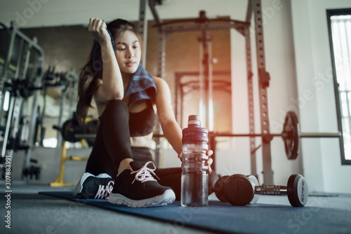 Young woman drinking water and taking a break after workout in gym,fitness concept.
