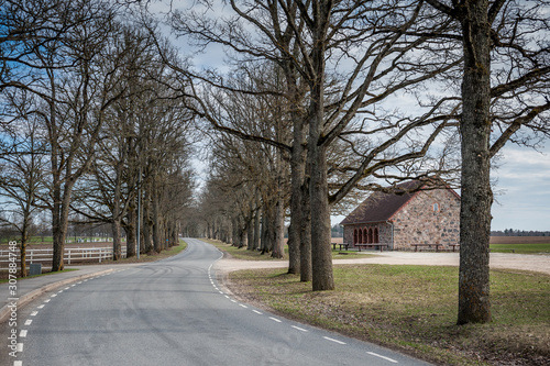 Winding road leading through manor buildings. Early spring landscape. Communal granary, Olustvere manor. Estonia.