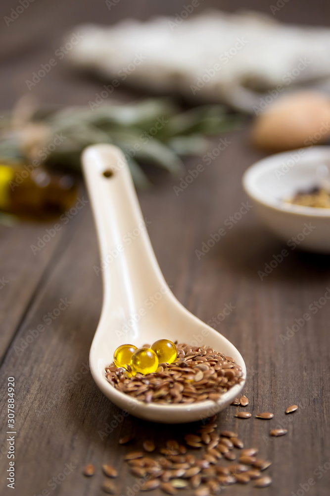 Flaxseed oil in pills on a wooden background. Phytotherapy. Linum usitatissimum oil. Homeopathy. Line seed oil. Alternative medicine. Flaxseed oil in pills on a wooden background. Phytotherapy. Linum usitatissimum oil. Homeopathy. Line seed oil. Alternative medicine.