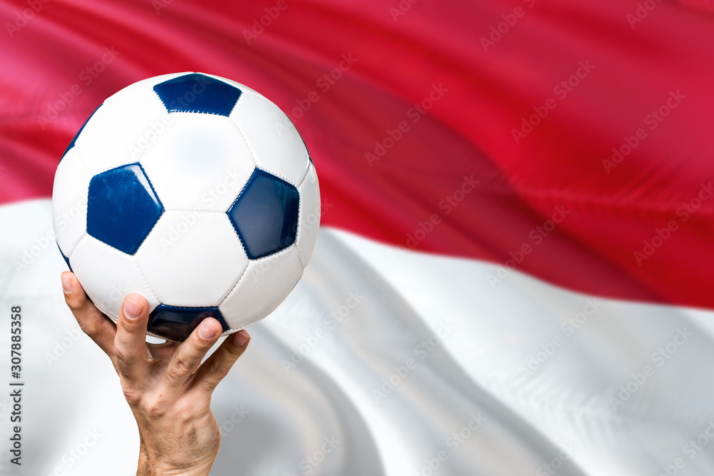 Indonesia soccer concept. National team player hand holding soccer ball with country flag background. Copy space for text. Indonesia soccer concept. National team player hand holding soccer ball with country flag background. Copy space for text.