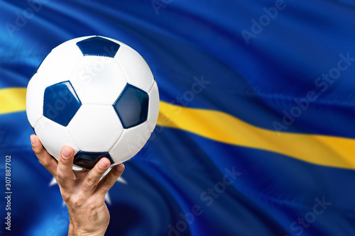 Nauru soccer concept. National team player hand holding soccer ball with country flag background. Copy space for text.