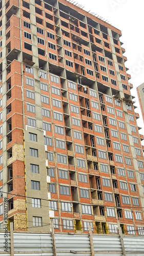 Multi-storey apartment buildings are being built, only red brick and window openings.