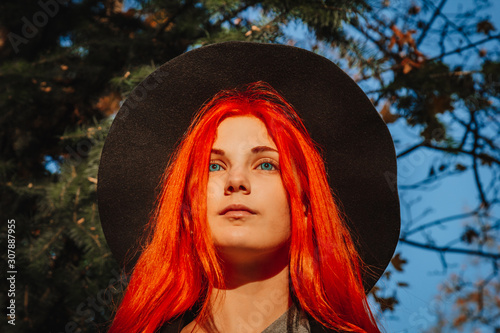 фотографія Sexy beautiful redhead girl with long, strong and thick hair in a black hat and coat