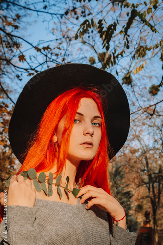 фотографія Sexy beautiful redhead girl with long, strong and thick hair in a black hat and coat