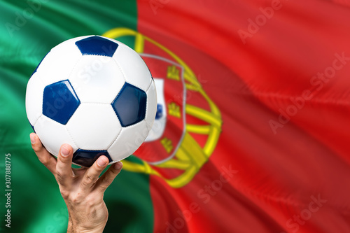 Portugal soccer concept. National team player hand holding soccer ball with country flag background. Copy space for text.