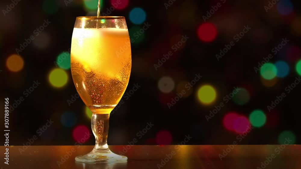 Pouring a Cup of Stella Artois beer with holiday colourful lights in background