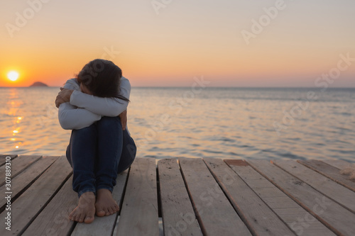 Billede på lærred beautiful Lonely woman sitting on a wooden bridge sunset