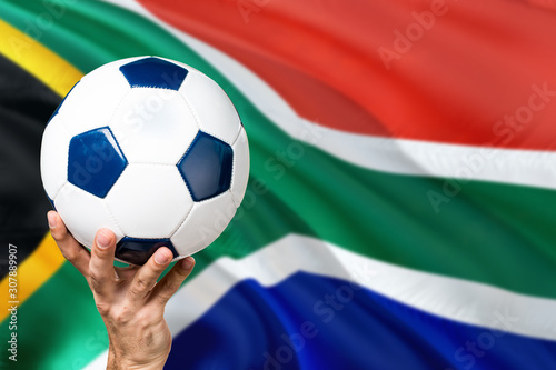 South Africa soccer concept. National team player hand holding soccer ball with country flag background. Copy space for text.
