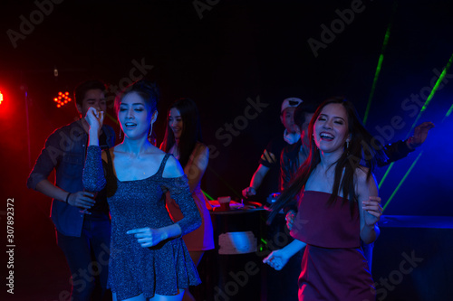 Holiday travel celebrations concept, group of people dancing together with enjoying at colourful night party club.