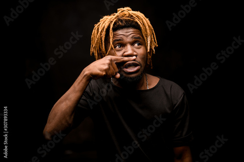 Canvas-taulu Black man with blonde dreadlocks posing in the dark outfit with the emotional fa