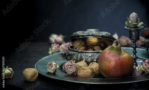 Pear, chestnuts and walnuts on a background of silver vintage accessories