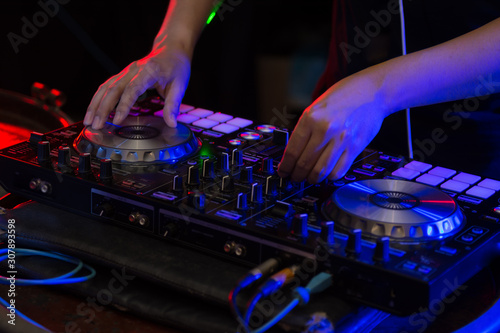 Sound engineer on mixer, close up of DJ hands on stage mixing, disc jockey and mix tracks on sound mixer controller, playing music at bar, disco tech or night club party. 