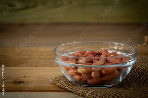 arachidi con pelle in ciotola di vetro su tavolo di legno