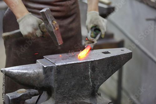 Forging an iron handmade product in a craft forge workshop