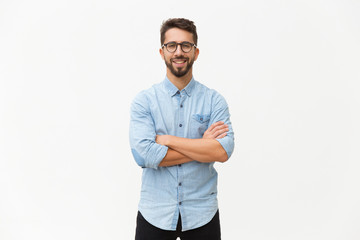 Happy laughing guy posing with arms folded. Handsome young man in casual shirt and glasses standing isolated over white background. Male portrait concept