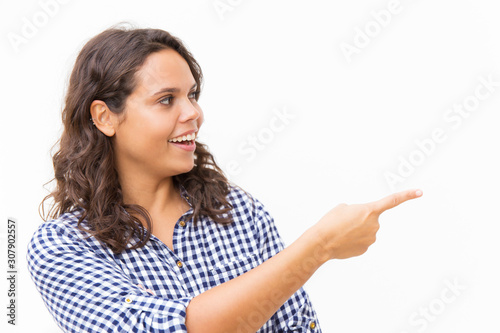 Happy joyful female customer presenting empty copy space near her. Young woman in casual checked shirt standing isolated over white background. Promotion concept