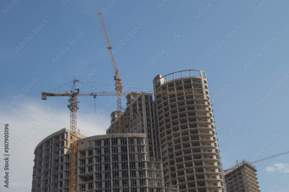 Working on place with many tall buildings under construction and cranes