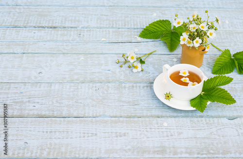 Healthy Herbal Flower tea. Tea cup with wild strawberry Flowers and leaves on wooden table. Herbal Medicine. Phytotherapy Medicinal Herbs. Copy space photo