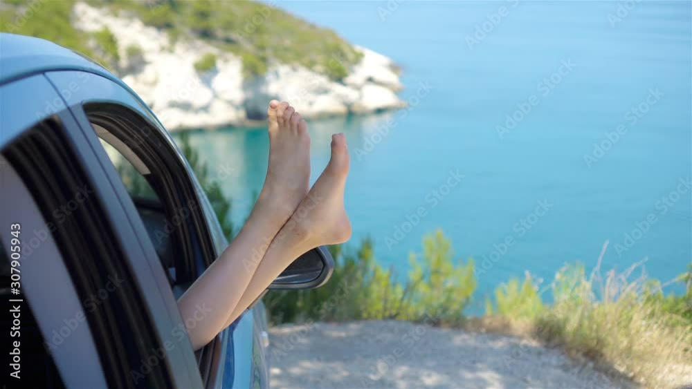 Close up of little girl feet showing from car window background sea Close up of little girl feet showing from car window background sea