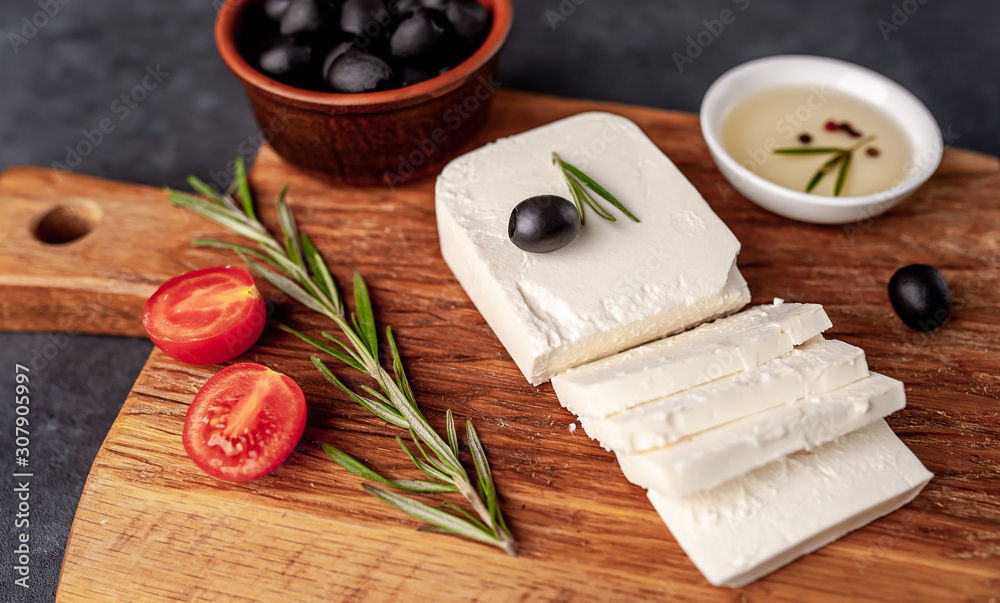 feta cheese, with rosemary, tomatoes, olives on a stone background