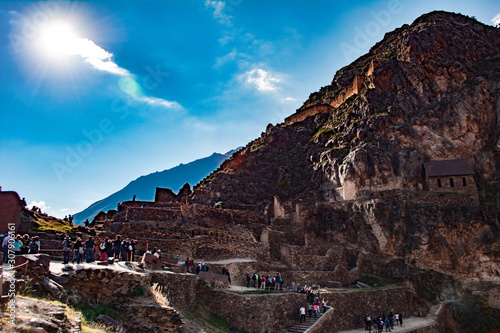 Mountain of Ollantaytambo ruins in Cusco with tourists walking.