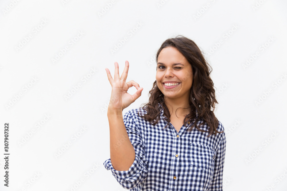 Joyful female customer making OK gesture, looking at camera, smiling. Young woman in casual checked shirt standing isolated over white background. Advertising concept Joyful female customer making OK gesture, looking at camera, smiling. Young woman in casual checked shirt standing isolated over white background. Advertising concept