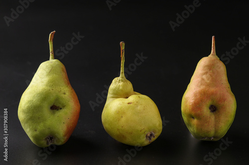 Fototapeta Naklejka Na Ścianę i Meble -  Ugly Ripe Pears are located on a dark background, horizontal orientation