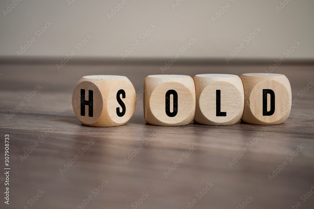 Cubes and dice showing the words hold and sold on wooden background Cubes and dice showing the words hold and sold on wooden background