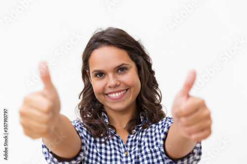Satisfied female customer making Like gesture with both hands, looking at camera, smiling. Young woman in casual checked shirt standing isolated over white background. Customer rate concept © Mangostar