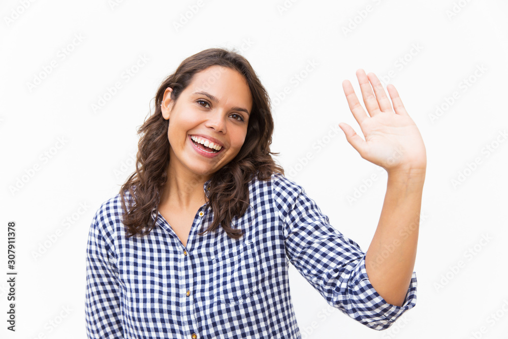 Happy sweet student girl waving hello at camera. Young woman in casual checked shirt standing isolated over white background. Greeting or communication concept Happy sweet student girl waving hello at camera. Young woman in casual checked shirt standing isolated over white background. Greeting or communication concept