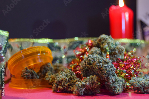 dried cannabis flowers and grinder with christmas decorations to celebrate the new year