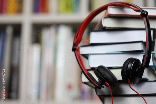 headphones and a stack of books, listening to audio books and traditional reading © Olga